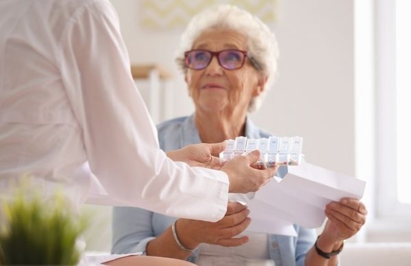 Eine ältere Frau bekommt Arzneimittelversorgung